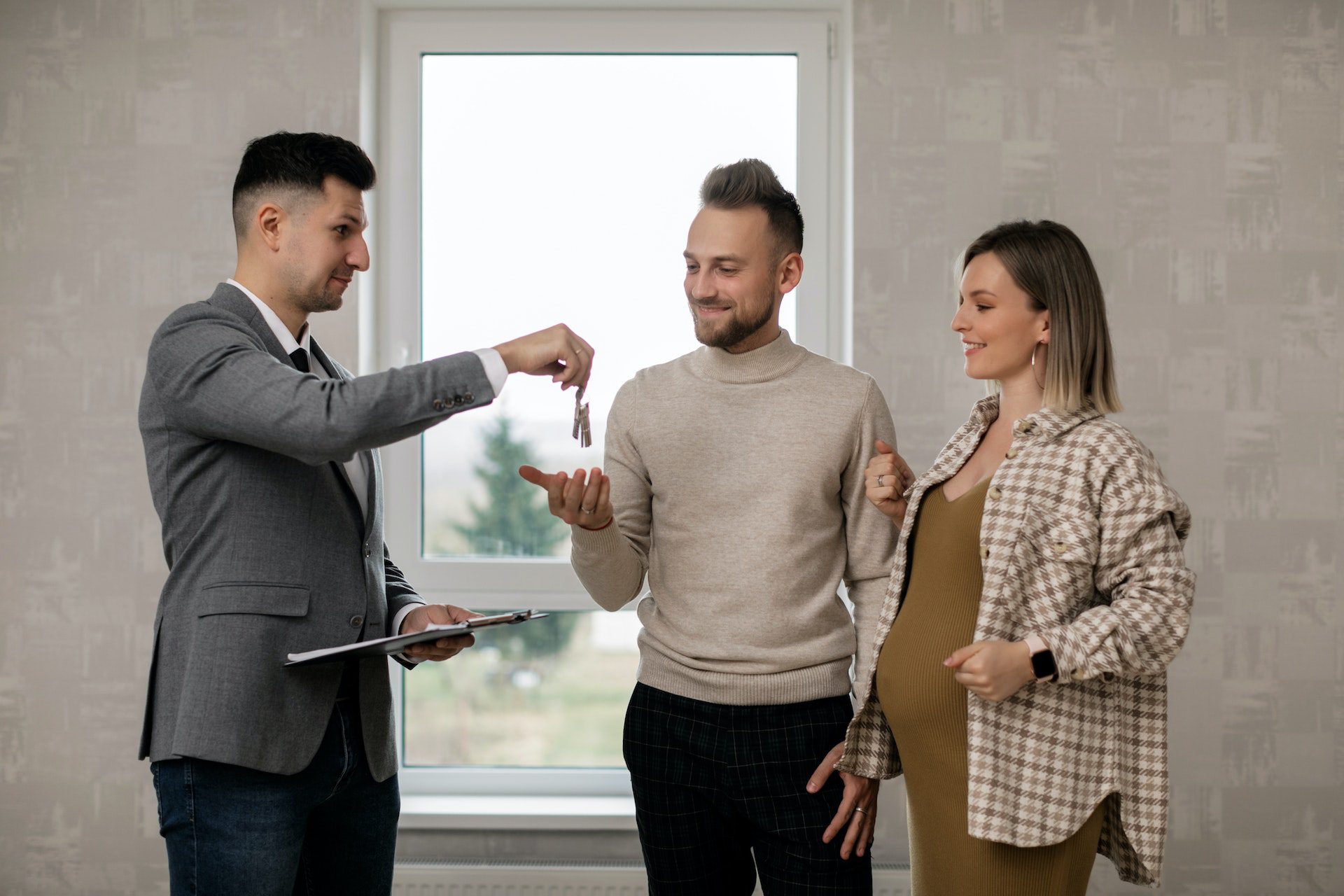 A Real Estate Agent Handing the Key to the New Homeowners<br />
